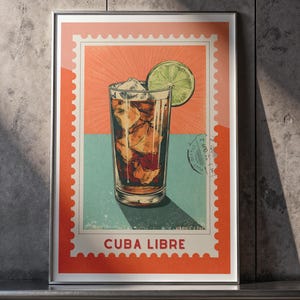 Puede incluir: Lámina artística enmarcada que representa un cóctel Cuba Libre. El diseño, con forma de sello postal, muestra un vaso alto con hielo y una bebida oscura, adornado con una rodaja de lima. Las palabras "CUBA LIBRE" están impresas en la parte inferior.
