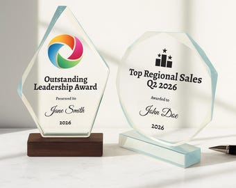 May include: Two clear glass awards with text. The left award is diamond-shaped with a colorful logo and reads "Outstanding Leadership Award" and "Jane Smith 2026." The right award is round and reads "Top Regional Sales Q2 2026" and "John Doe 2026."