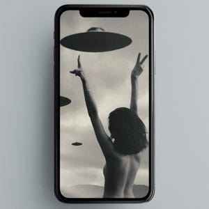 May include: Black and white image of a smartphone displaying a vintage-style illustration. The artwork depicts a person with arms raised towards three UFOs. The person is facing away from the viewer, with their back visible. The background suggests a landscape.