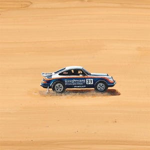 K&ouml;nnte beinhalten: Ein Miniatur-Porsche-Rennwagen in Blau, Wei&szlig; und Orange mit der Nummer 33 auf der Seite. Auf dem Auto stehen die Worte "Roughmans Porsche Dunlop" aufgedruckt. Das Auto steht vor einem beigen Hintergrund.