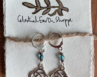 May include: Silver Celtic knot earrings with teal blue glass beads hanging from silver hoops. The earrings are on a white background with the text "Celestial Earth Shoppe" written in black.
