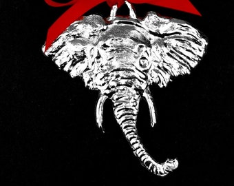 Pode incluir: Ornamento de elefante de prata com uma fita vermelha. O ornamento está preso a um cartão que diz "K&S Pewter".