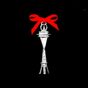 May include: A silver Space Needle charm with a red bow on top. The charm is a popular souvenir from Seattle, Washington.
