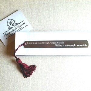 May include: A silver bookmark with a red tassel. The bookmark has the quote "Knowing is not enough, we must apply. Willing is not enough, we must do." engraved on it.
