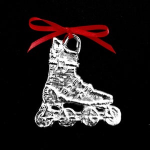 May include: A silver roller skate ornament with a red ribbon. The skate has a detailed design and is a great addition to any Christmas tree.