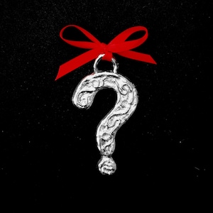 May include: A silver question mark ornament with an ornate design, hanging from a red ribbon.