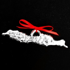 May include: A silver charm in the shape of the island of Java with the word "JAVA" embossed on it. A red ribbon is tied around the charm.