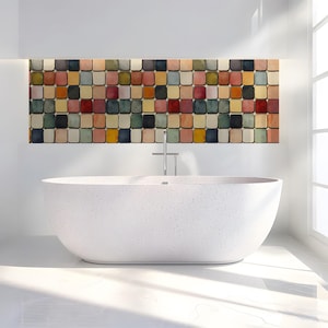 May include: A white freestanding oval bathtub with a speckled finish sits in front of a wall featuring a grid of small, rounded square tiles in various muted colors including red, blue, yellow, green, and beige, with a chrome faucet centered above.