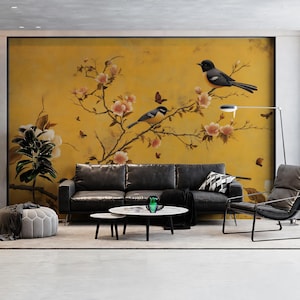 Könnte beinhalten: Ein Wohnzimmer mit einem schwarzen Ledersofa, einem modernen Stuhl und einem runden Couchtisch. Der Mittelpunkt ist ein großes, gelbes Wandbild mit Vögeln, Blumen und Schmetterlingen. Eine Stehlampe und eine Topfpflanze vervollständigen die Einrichtung.