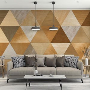 May include: A modern living room featuring a beige sofa with decorative pillows, a white coffee table, and a geometric wooden wall. Two pendant lights hang above the sofa. The wall is made of triangles in various shades of brown.