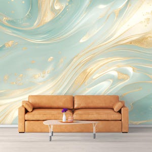Könnte beinhalten: Ein Wohnzimmer mit einem hellbraunen Ledersofa, einem kleinen ovalen Couchtisch und einer Wand mit einem abstrakten Design in Türkis und Gold. Das Sofa hat zwei Kissen und ein kleines Kissen. Auf dem Couchtisch steht eine Vase mit lila Blumen.