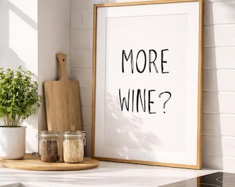 May include: A rectangular wall art print in a light wood frame featuring the black text MORE WINE? centred on a white background. The print is displayed in a kitchen setting with a wooden cutting board and two glass jars of spices nearby.