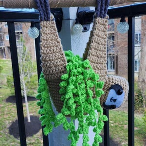 Jardinera colgante con forma de perezoso y planta