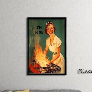 May include: A framed vintage print showing a woman in a white dress and apron smiling as flames burst from a stove. The text "I'M FINE" is in the upper left corner. The print is in a black frame.