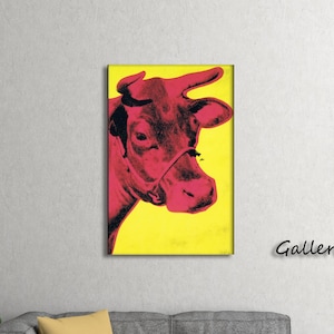 May include: A pop art style print of a cow's head in shades of red against a bright yellow background. The artwork is framed and labeled "Gallery Wrap". The cow's head is in profile, with a halter visible.