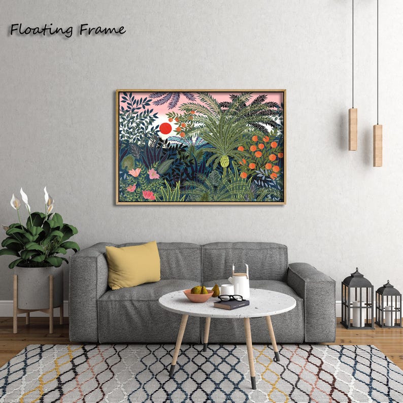 May include: A framed art print featuring a vibrant jungle scene with lush green foliage, orange fruit, and a red sun against a pink sky. The words "Floating Frame" are in the upper left corner. The artwork is displayed above a gray sofa with a yellow pillow.