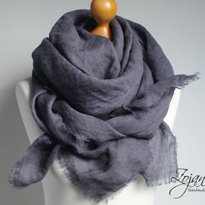 May include: A charcoal grey linen scarf with frayed edges. The scarf is draped over a white mannequin.
