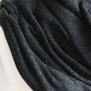 May include: A close-up of a dark gray knitted scarf with a soft, textured surface.
