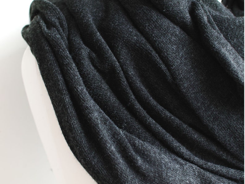 May include: A close-up of a dark gray knitted scarf with a soft, textured surface.