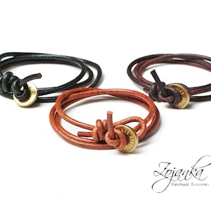 Puede incluir: Tres pulseras de cuero con detalles de latón. Cada pulsera es de un color diferente: negro, marrón y burdeos. Las pulseras están atadas con un nudo y tienen una etiqueta de latón con la palabra "Tries" grabada.
