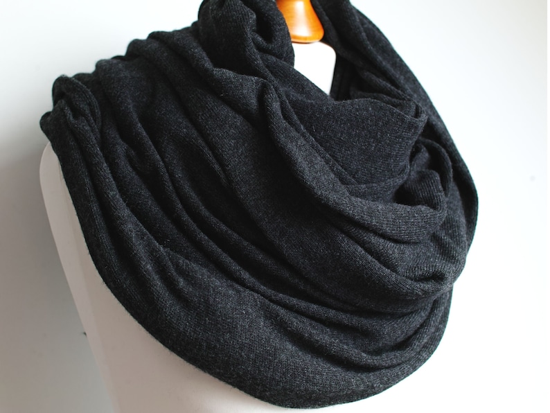 May include: A charcoal gray infinity scarf made of soft knit fabric.