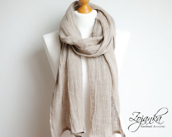 May include: A light brown linen scarf draped over a mannequin. The scarf is made of a soft, natural fabric and has a simple, elegant design.