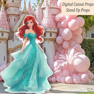 A digital cutout prop of a Mermaid princess in a teal gown with red hair, positioned before a pink castle and a pink balloon display. The text "Digital Cutout Props Stand Up Props" is visible.