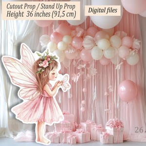 Può includere: Un ritaglio di fata rosa, alto 91,5 cm, con una corona di fiori e una farfalla. Lo sfondo presenta palloncini rosa e bianchi, scatole regalo e tende trasparenti, creando una scena di festa stravagante. File digitali.