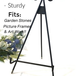 May include: Black metal easel stand, 13 inches tall, with a sturdy design. It is designed to hold garden stones, picture frames, and artwork.