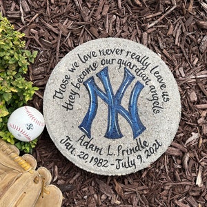 Puede incluir: Un memorial de piedra gris con un logotipo de los New York Yankees azul y blanco pintado en &eacute;l. La piedra tiene el texto "Those we love never really leave us they become our guardian angels" y "Adam L. Prindle Jan. 20, 1982 - July 9, 2021".