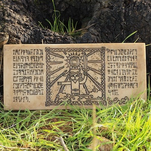 Puede incluir: Placa rectangular de color beige con una ilustración negra de un personaje sosteniendo una espada, un sol y nubes. La placa tiene texto en un idioma desconocido a ambos lados de la ilustración. Descansa sobre hierba verde.