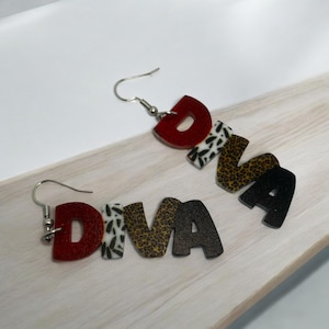 May include: A pair of earrings with the word "DIVA" spelled out in red, black, white, and brown letters. Each letter has a different animal print pattern.