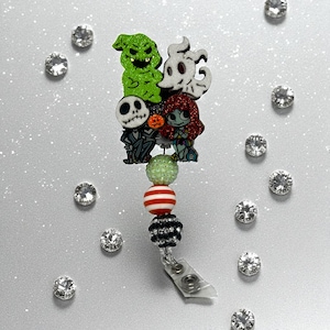 May include: A retractable badge reel featuring characters from The Nightmare Before Christmas. The characters are atop a beaded design with green, red, and black beads. The reel has a silver clip.