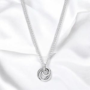 May include: A silver necklace with a pendant featuring three interlocking circles, each with a row of small clear cubic zirconia stones.