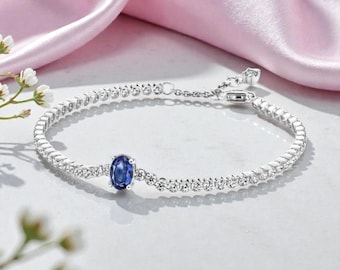 Pulsera de tenis de plata con piedra central azul ovalada y detalles en pavé transparente. Elegante y ajustable, regalo de joyería para mujer.