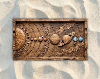 May include: A wooden relief carving of the solar system, featuring the sun, planets, and orbital paths. The planets are depicted in varying sizes and colors, with Saturn's rings prominently displayed. The artwork is set within a rectangular frame.