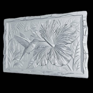 May include: A rectangular white wall plaque featuring a high-relief carving of a hummingbird hovering near a large hibiscus flower. The design includes detailed foliage in the background and a textured, uneven border framing the central scene.