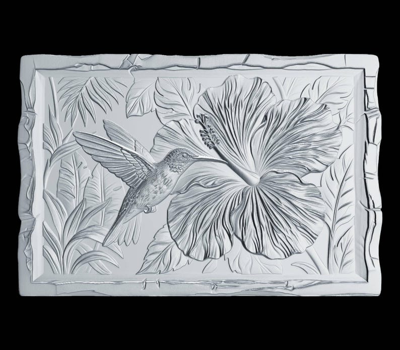May include: A rectangular white wall plaque featuring a high-relief carving of a hummingbird hovering near a large hibiscus flower. The background displays detailed tropical foliage, and the entire piece has a textured, stone-like border.