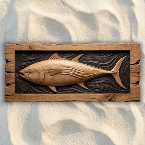 May include: A rectangular wooden wall plaque featuring a relief carving of a tuna fish swimming through stylized waves. The fish is rendered in a light brown wood tone, while the background waves are stained a dark brown, all framed by a rustic border.