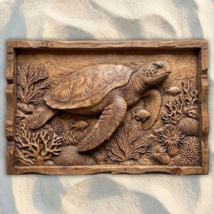 May include: A detailed wooden carving of a sea turtle swimming among coral and small fish. The artwork is set within a rectangular frame, showcasing the turtle's shell and flippers. The carving is in shades of brown.