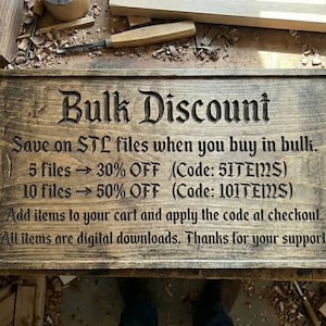 Pu&ograve; includere: Un cartello rettangolare in legno con la scritta "Bulk Discount". Offre sconti sui file STL: 30% di sconto per 5 file e 50% di sconto per 10 file. Attrezzi da falegname sullo sfondo.