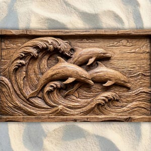 May include: A rectangular, wooden wall art piece featuring a detailed relief carving of three dolphins leaping through ocean waves. The dolphins and waves are carved in a natural wood tone, creating a three-dimensional effect.