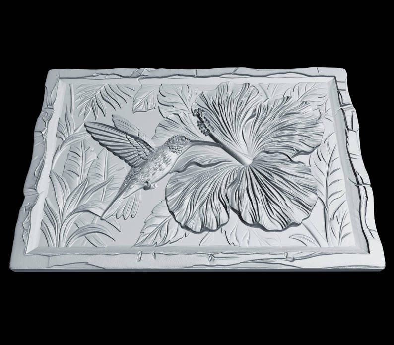 May include: A rectangular white wall plaque featuring a detailed relief carving of a hummingbird hovering near a large hibiscus flower. The design includes textured foliage in the background and a decorative border with a rough, stone-like edge.