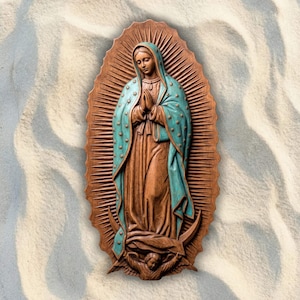 Peut inclure: Une plaque murale sculptée représentant la Vierge de Guadalupe, avec une silhouette aux tons bois brun portant un manteau bleu sarcelle étoilé d'or, debout sur un croissant de lune avec un ange ailé à la base, entourée d'un halo rayonnant.