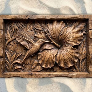 May include: A wooden relief carving depicting a hummingbird and hibiscus flower. The artwork is framed with a rustic, textured border. The carving is in shades of brown, showcasing detailed craftsmanship. The measurements are in centimetres.