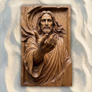 Könnte beinhalten: Eine rechteckige Wandplatte aus Holz mit einer detaillierten Reliefschnitzerei einer bärtigen Figur mit langem Haar, die in drapierten Gewändern gekleidet ist. Die Figur ist mit einem nach vorne ausgestreckten Arm und offener Handfläche dargestellt.