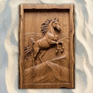 Puede incluir: Tallado en relieve de madera detallado de un caballo encabritado. El caballo se representa con melena y cola fluidas, sobre un paisaje. La obra de arte está enmarcada por un borde rústico de borde natural, que muestra la veta y la textura de la madera. La pieza es de un marrón cálido y natural.