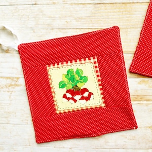 Può includere: Due presine rosse a pois bianchi con un anello bianco per appenderle. Ogni presina presenta un disegno quadrato ricamato di un pomodoro o ravanelli su sfondo crema con un bordo a quadretti. Arredamento cucina.