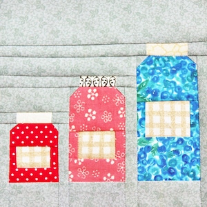May include: Three fabric jars with different patterns. The jar on the left is red with white polka dots, the middle jar is pink with white flowers, and the jar on the right is blue with white and yellow checked patterns.