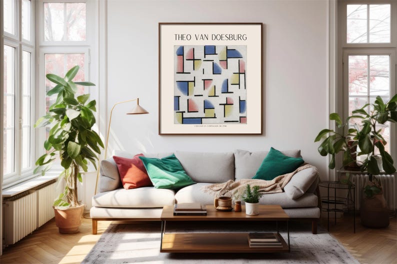 May include: A framed print of a geometric abstract art piece by Theo van Doesburg. The artwork features a white background with colorful squares, rectangles, and semi-circles in shades of blue, yellow, pink, and red. The print is hanging on a white wall in a living room setting.